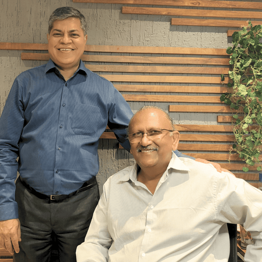 Atiroh co-founder and managing partner posing together in an office setting, standing in front of a wooden wall with greenery.