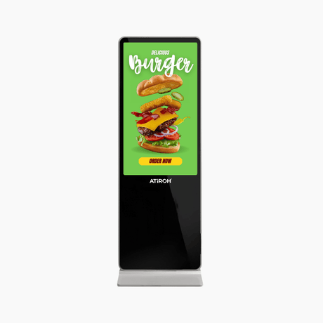 Atiroh digital display kiosk featuring a burger advertisement with a green background and "Order Now" button on a white backdrop.