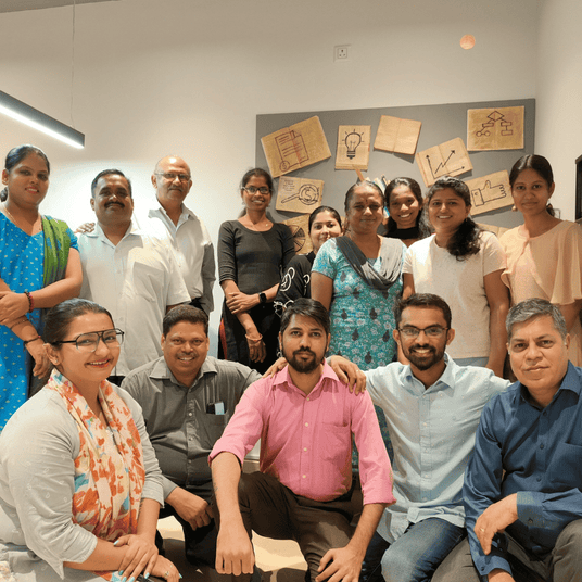 Atiroh team group photo in an office setting with motivational posters on the wall, representing teamwork and company culture.
